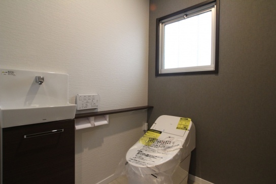 １階のトイレ交換とともに手洗いカウンターを新設（TOTO CG-1タンクレス）。一面の壁紙をアクセントグレーに
