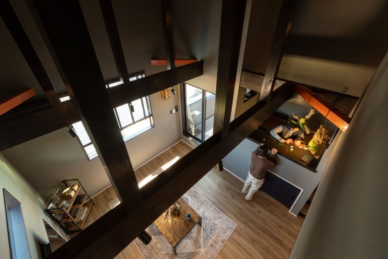 ロフトから見下ろしたリビングとワークスペース。火打ち梁のオレンジ色がアクセントに
